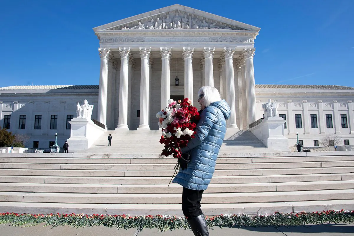 A woman helps lay 3,000 carnations to represent the approximately 3,000 abortions that occur in the United States every day, on the 46th anniversary of the Roe v Wade decision, in front of the U.S. Supreme Court in Washington on Jan. 22, 2019. (Jim Watson/AFP via Getty Images)