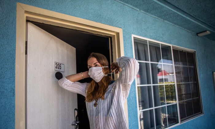 A woman puts a mask on at a motel that provided rooms to homeless people through the NGO St. Joseph Center, in Venice Beach, Calif., on April 26, 2020. (Apu Gomes/AFP via Getty Images)
