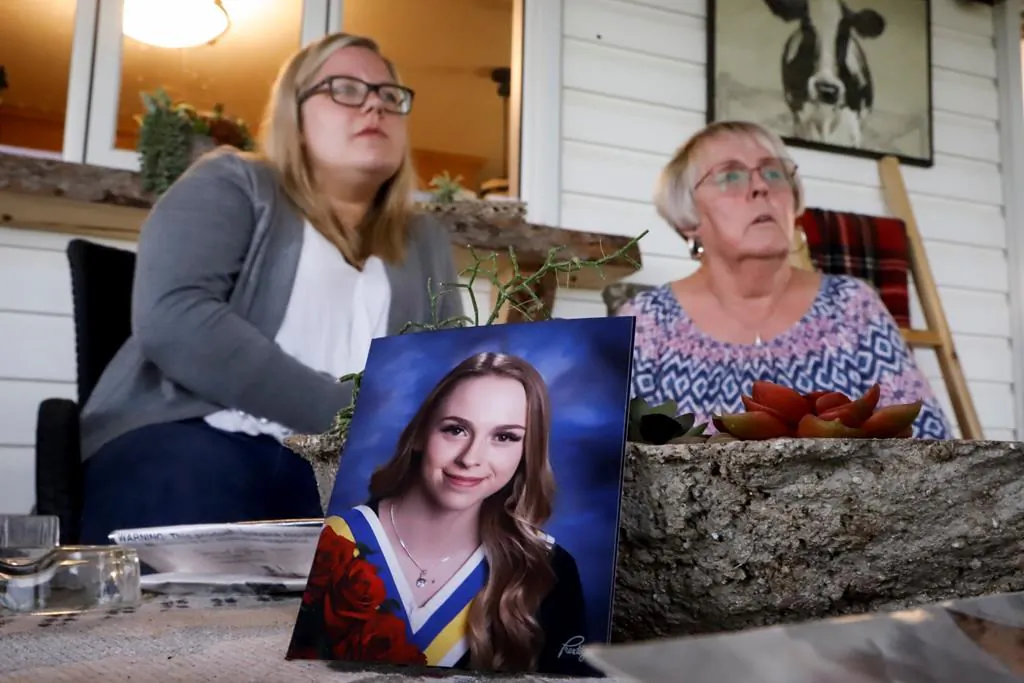 Heather Thomson (R) and her granddaughter Jillisa Thomson speak about their experiences during the Pine Lake tornado at a 2018 graduation photo of "miracle baby" Ashley Thomson at their home near Pine Lake, Alta., on July 12, 2020. (Jeff McIntosh/The Canadian Press)