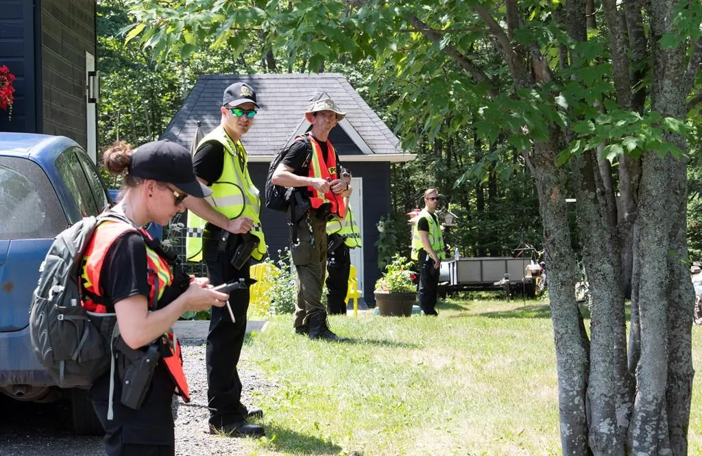 Police officers and volunteers stand in line before entering the woods to search on July 10, 2020 in Saint-Apollinaire Que. Police  issued an Amber Alert Thursday for two young girls and their 44-year-old father who investigators believe disappeared following a highway car crash. The bodies of the two girls were later found in a wooded area of St-Apollinaire.  (Jacques Boissinot/The Canadian Press)