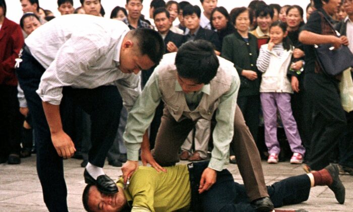 Police detain a Falun Gong protester in Tiananmen Square as a crowd watches, in Beijing on Oct. 1, 2000.  (AP Photo/Chien-min Chung)