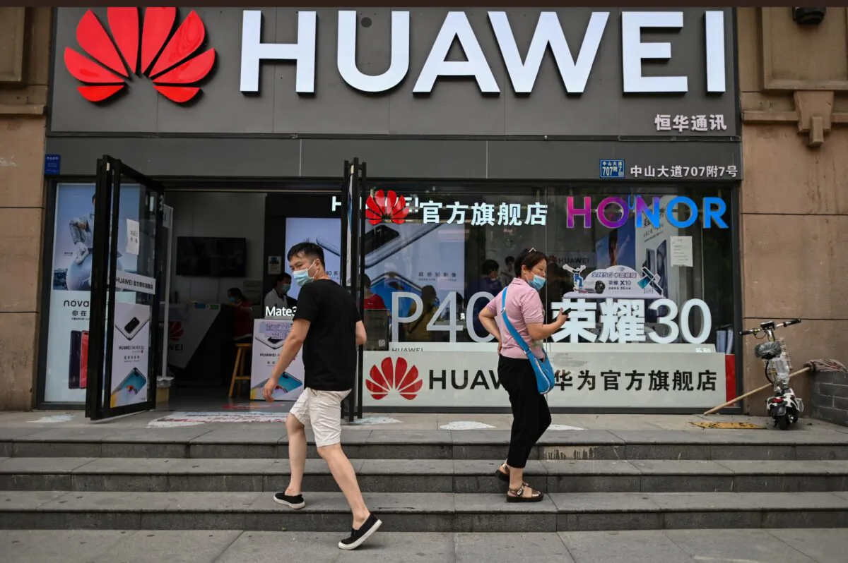 People wearing masks walk outside a Huawei store in Wuhan, Hubei Province, China, on May 26, 2020. (HECTOR RETAMAL/AFP via Getty Images)