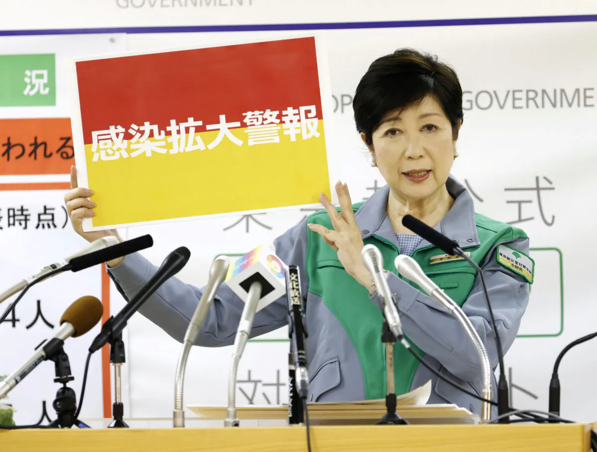 Tokyo Gov. Yuriko Koike shows a banner reading 'Infection spread alert' as she attends a news conference on the latest situation regarding the coronavirus outbreak, in Tokyo, Japan, on July 15, 2020. (Kyodo/via Reuters)
