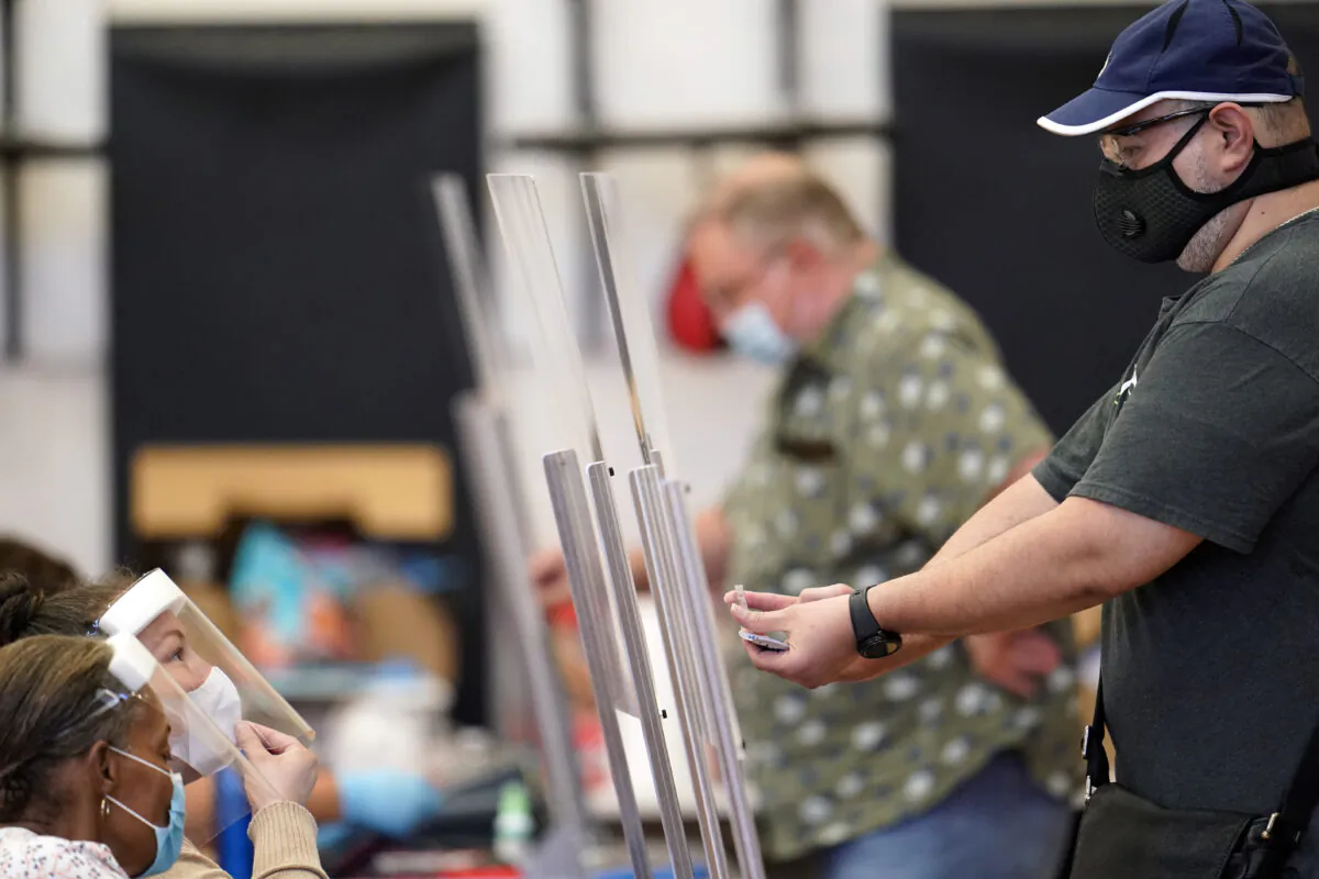 A voter (R) shows his identification to a Harris County election clerk before voting in Houston, Texas, on July 14, 2020. (David J. Phillip/AP Photo)
