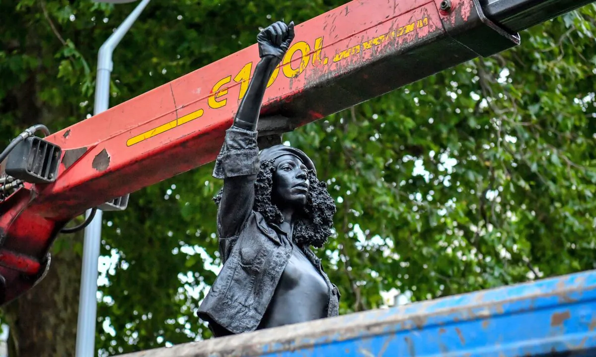 Contractors remove the statue "A Surge of Power (Jen Reid) 2020" by artist Marc Quinn, which had been installed on the site of the fallen statue of the slave trader Edward Colston, in Bristol, England, on July 16, 2020. (Ben Birchall/PA via AP)