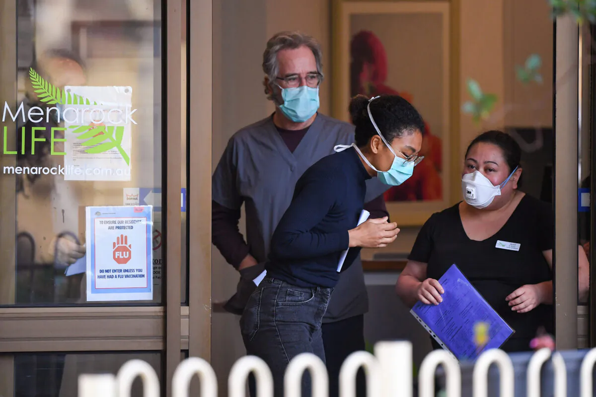 People wearing face masks are seen at the entrance of the Menarock Life aged care facility, Essendon, Melbourne, Australia on July 14, 2020, (William West/AFP via Getty Images)