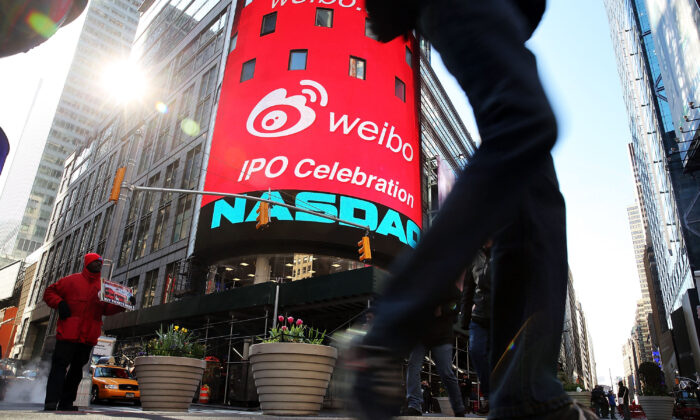 People walk by the Nasdaq exchange in Times Square moments before China's Weibo began trading on the Nasdaq exchange under the ticker symbol WB in New York City, on April 17, 2014. (Spencer Platt/Getty Images)