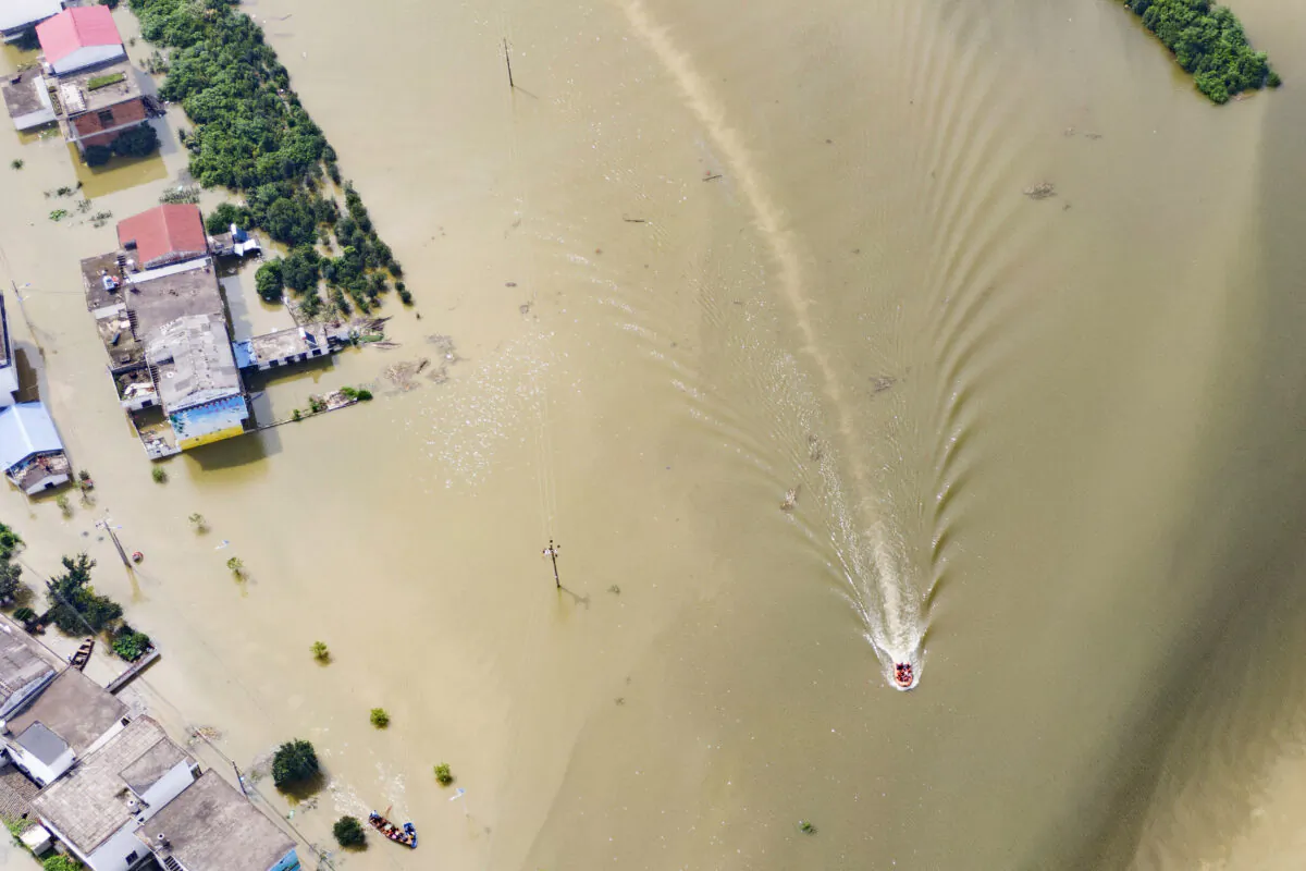 In this aerial photo, rescue workers on a raft are seen moving through flood waters to help evacuate trapped residents in Sanjiao Township of Yongxiu County in central eastern China's Jiangxi Province on July 13, 2020. (Zhang Haobo/Xinhua via AP)