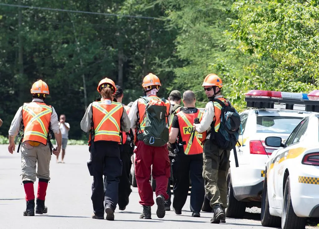 Police officers and volunteers march to the woods to search in Saint-Apollinaire, Quebec, Canada, on July 10, 2020. (Jacques Boissinot/The Canadian Press)
