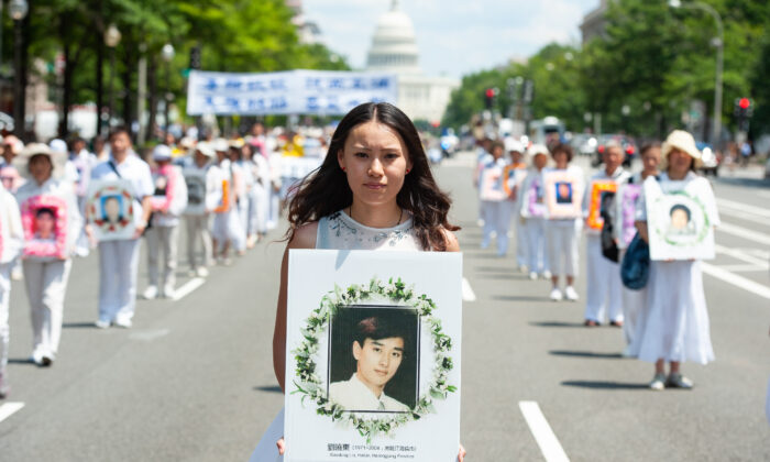 A woman holds a photo of a man killed by the Chinese regime's persecution of Falun Gong, during a parade in Washington on July 17, 2014. (Larry Dye/The Epoch Times)