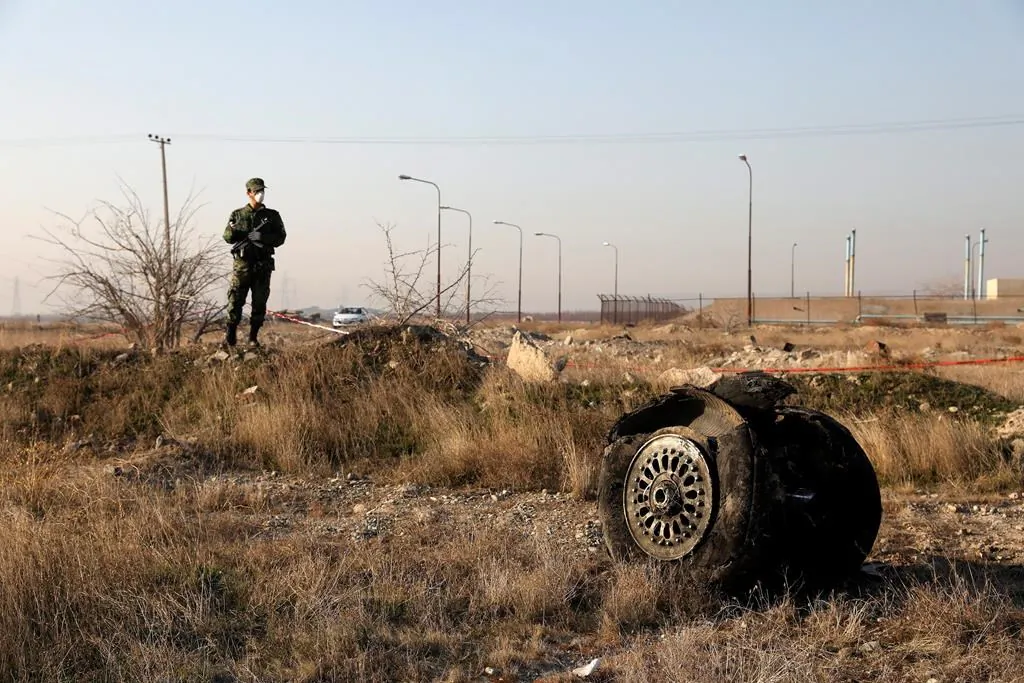 A police officer stands guard as debris is seen from a Ukrainian plane which crashed in Shahedshahr, southwest of the capital Tehran, Iran, January 8, 2020. (The Canadian Press/AP/Ebrahim Noroozi)