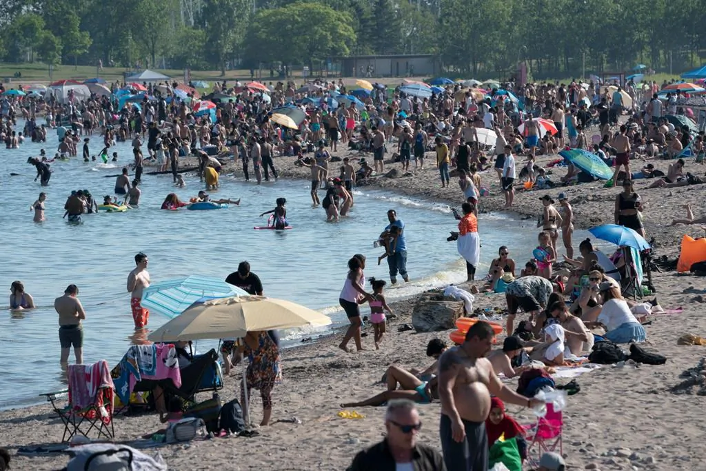 Scientists are warning that more young people are being infected with COVID-19, creating the potential for a severe outbreak. Thousands of people spend time on the beach by Lake Ontario in Toronto. on June 20, 2020. (The Canadian Press/Frank Gunn)