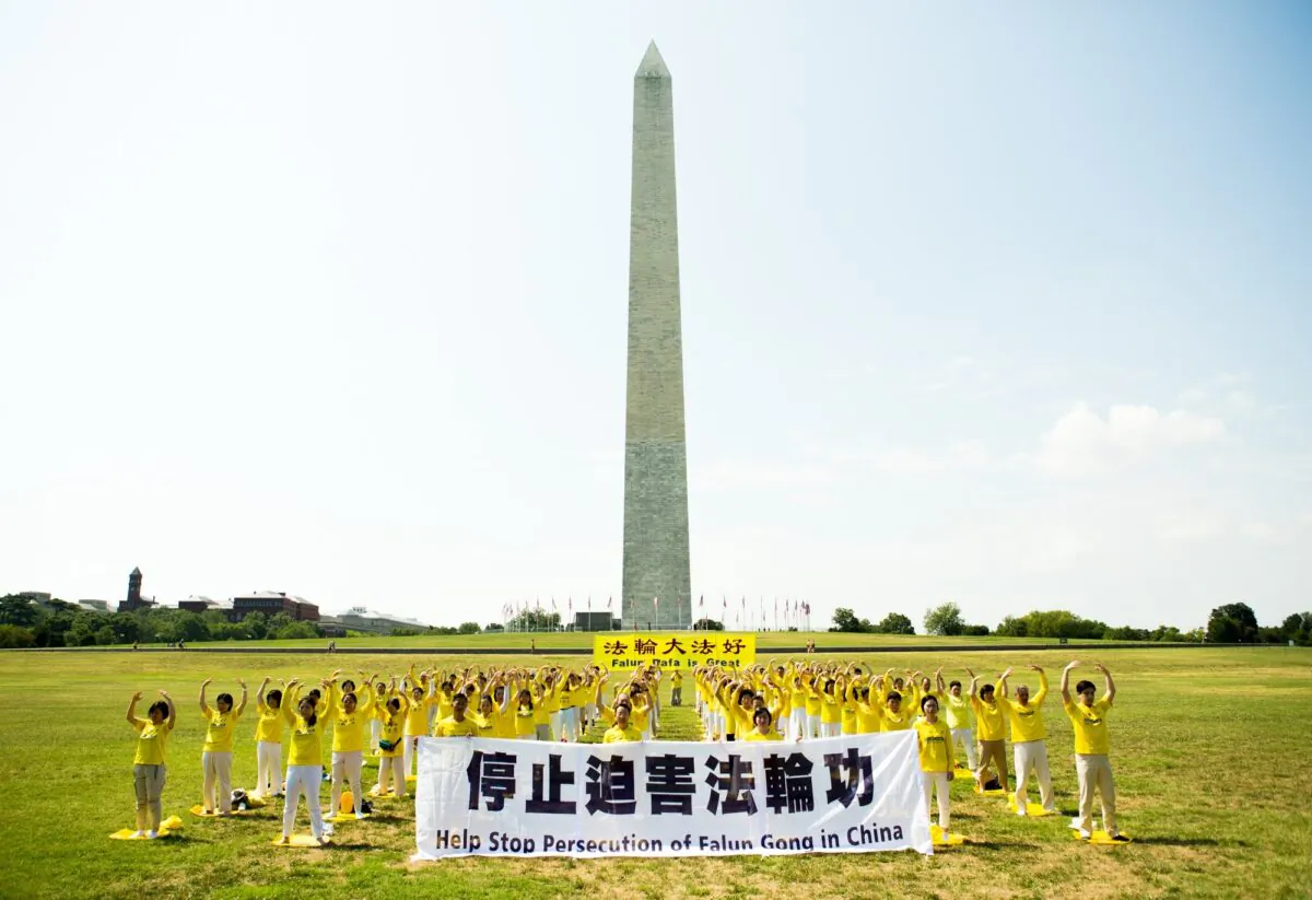 Over one hundred of Falun Gong practitioners are practicing exercises on the grass in front of the Washington Monument to urge the stopping of the CCP's persecution of their spiritual discipline, in Washington, D.C., on July 19, 2020. (Lisa Fan/The Epoch Times)