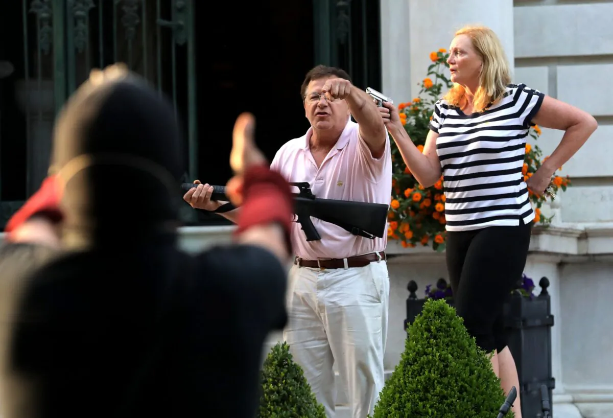 Armed homeowners Mark and Patricia McCloskey, stand in front their house along Portland Place to confront protesters marching to St. Louis Mayor Lyda Krewson's house in the Central West End of St. Louis, Mo., on June 28, 2020. (Laurie Skrivan/St. Louis Post-Dispatch via AP)