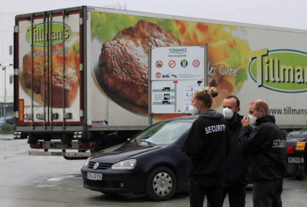 Security personnel stand in front of a meat truck