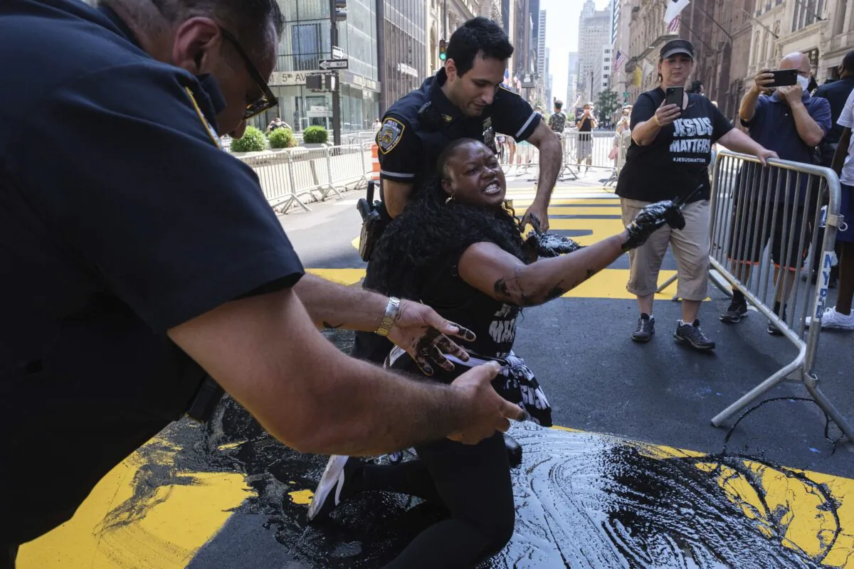 NYPD officers attempt to detain Bevelyn Beatty, who poured black paint on the Black Lives Matter mural outside of Trump Tower on Fifth Avenue in the Manhattan borough of New York, on July 18, 2020. (Yuki Iwamura/AP Photo)