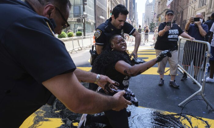NYPD officers attempt to detain Bevelyn Beatty, who poured black paint on the Black Lives Matter mural outside of Trump Tower on Fifth Avenue in the Manhattan borough of New York, on July 18, 2020. (Yuki Iwamura/AP Photo)