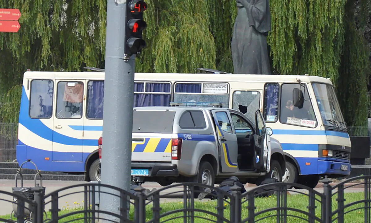 Ukrainian law enforcement officers lie on the ground behind a car near a passenger bus, which was seized by an unidentified person in the city of Lutsk, on July 21, 2020. (Tetiana Hrishyna/Reuters)