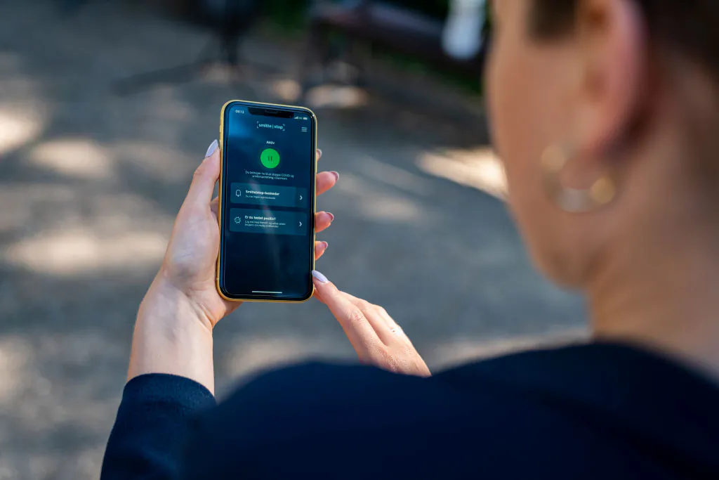 A woman holds a smartphone showing a new official COVID-19 infection tracing app in Copenhagen. Denmark, on June 18, 2020. (Martin Sylvest/Ritzau Scanpix/AFP via Getty Images)