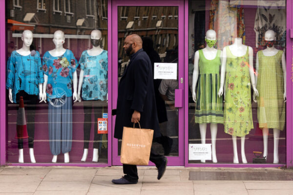 A man walks past a closed retail outlet in London