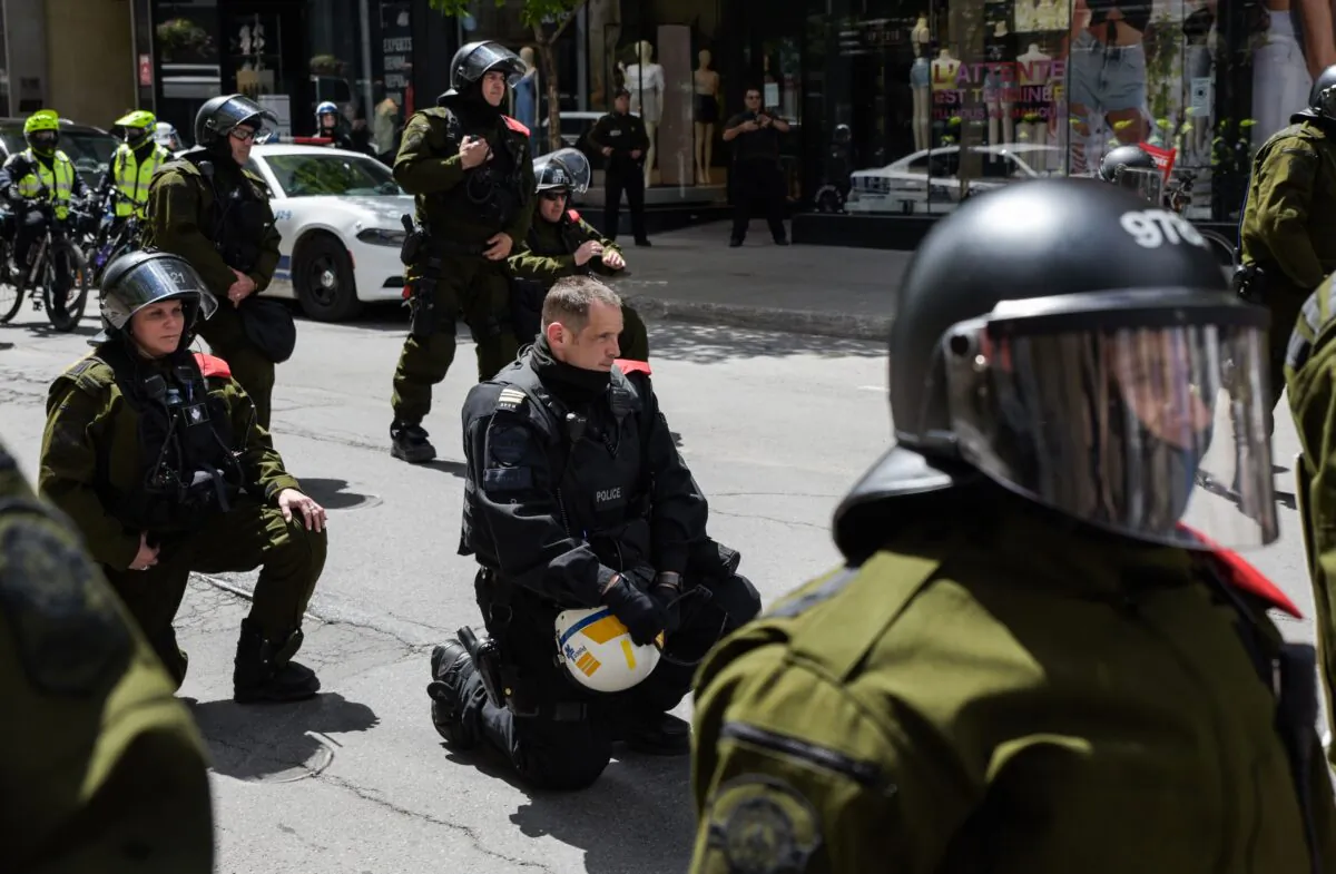 Police officers kneel behind a police line as protesters march in solidarity with protests in the United States over the killing of George Floyd, in Montreal on June 7, 2020. (Martin Oulett-Diotte/AFP via Getty Images)