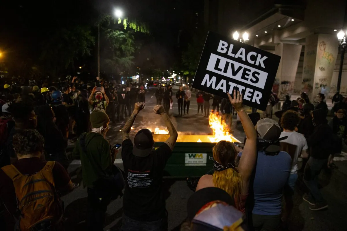 A waste receptacle was moved into the intersection of SW 3rd and Main and its contents set on fire as Portland protesters gathered downtown on July 10, 2020. (Dave Killen/The Oregonian via AP)