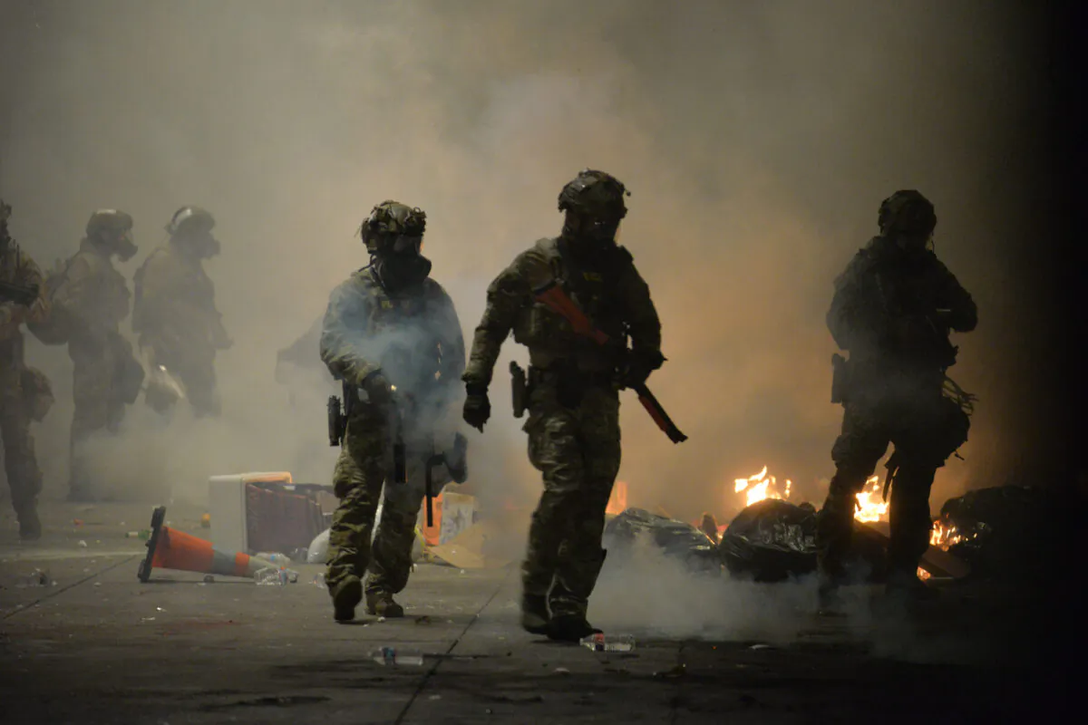 US Federal Police use crowd control methods to disperse protesters at the Multnomah County Justice Center in Portland, Oregon, on July 23, 2020. - Police fired teargas and fought running battles with protesters in Portland in the latest night of demonstrations against police brutality and the deployment of federal troops to US cities. (Photo by Ankur Dholakia / AFP) (Photo by ANKUR DHOLAKIA/AFP via Getty Images)