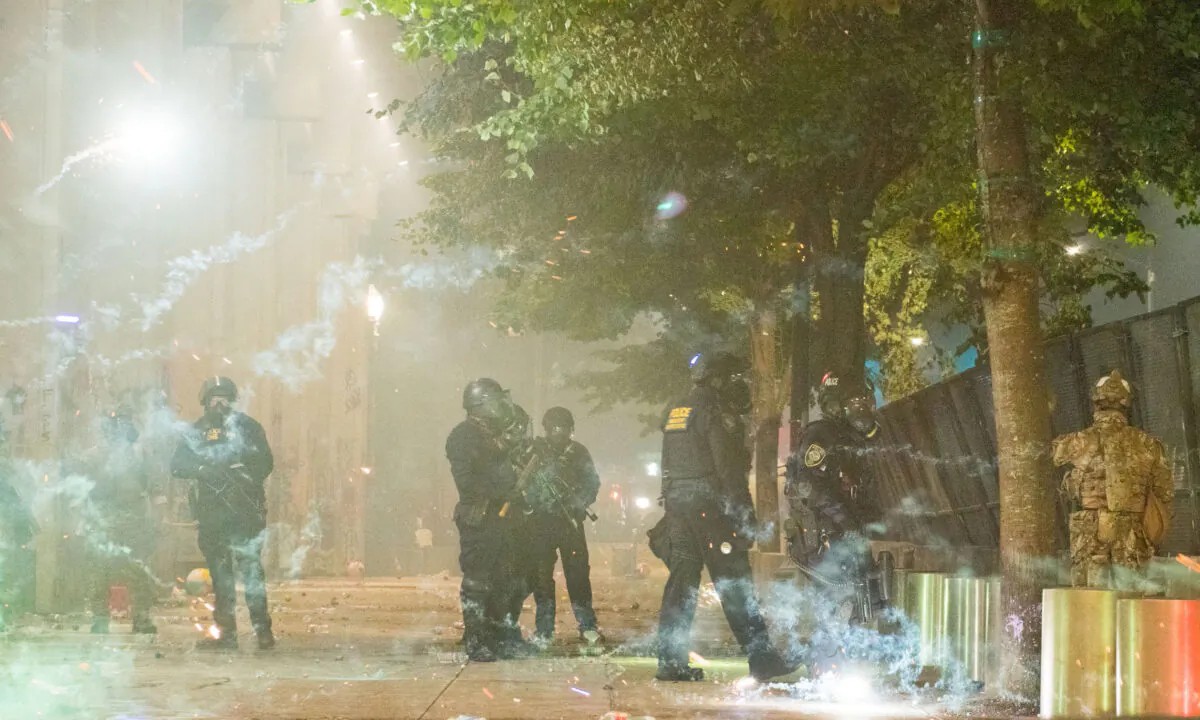 Fireworks go off near federal police guarding the Mark O. Hatfield federal courthouse in downtown Portland as federal officers confront rioters in Portland, Oregon, on July 24, 2020. (Kathryn Elsesser/AFP via Getty Images)