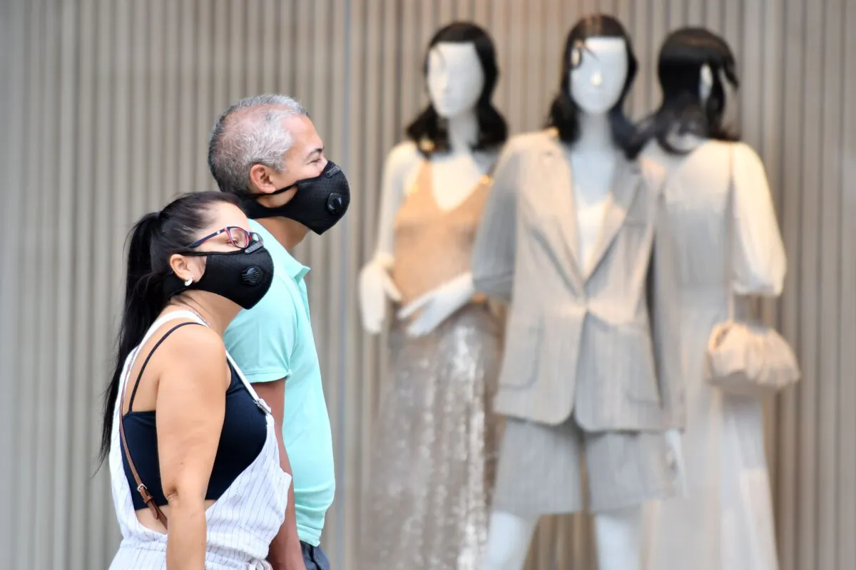 Shoppers wear masks as a precaution against the transmission of the novel coronavirus as they walk past a shop window on Oxford Street in London on July 14, 2020. (Justin Tallis/AFP via Getty Images)