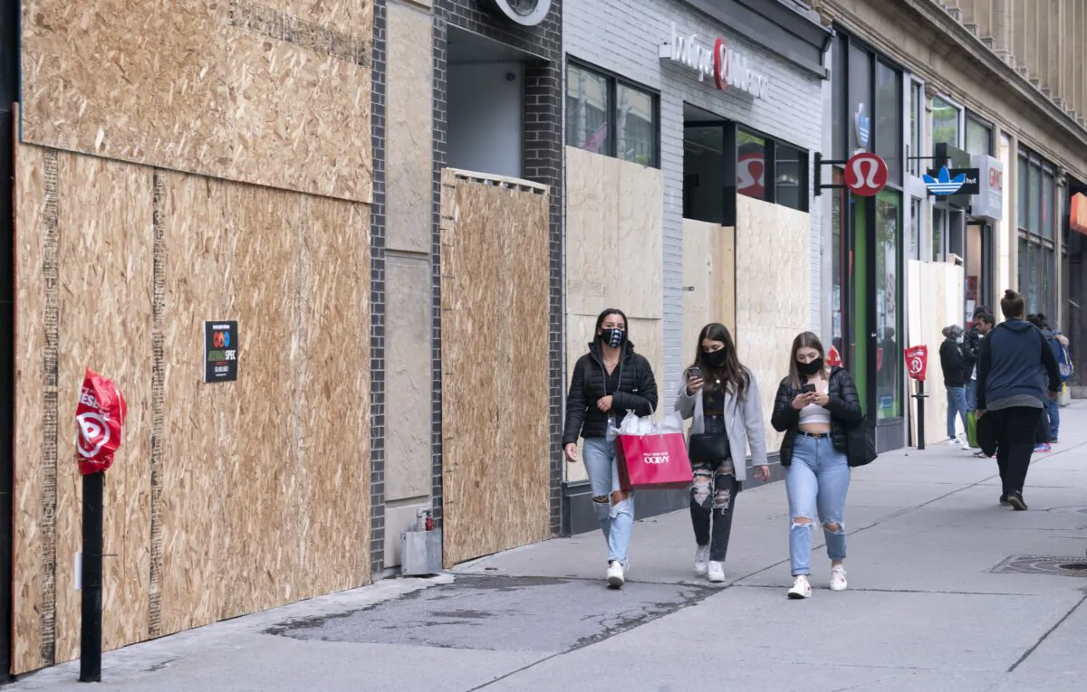 People walk past boarded up stores on Montreal's Sainte-Catherine Street on June 3, 2020. Every stalled business is a double-edged sword: lower tax revenues and more people eligible for unemployment benefits. (The Canadian Press/Paul Chiasson)