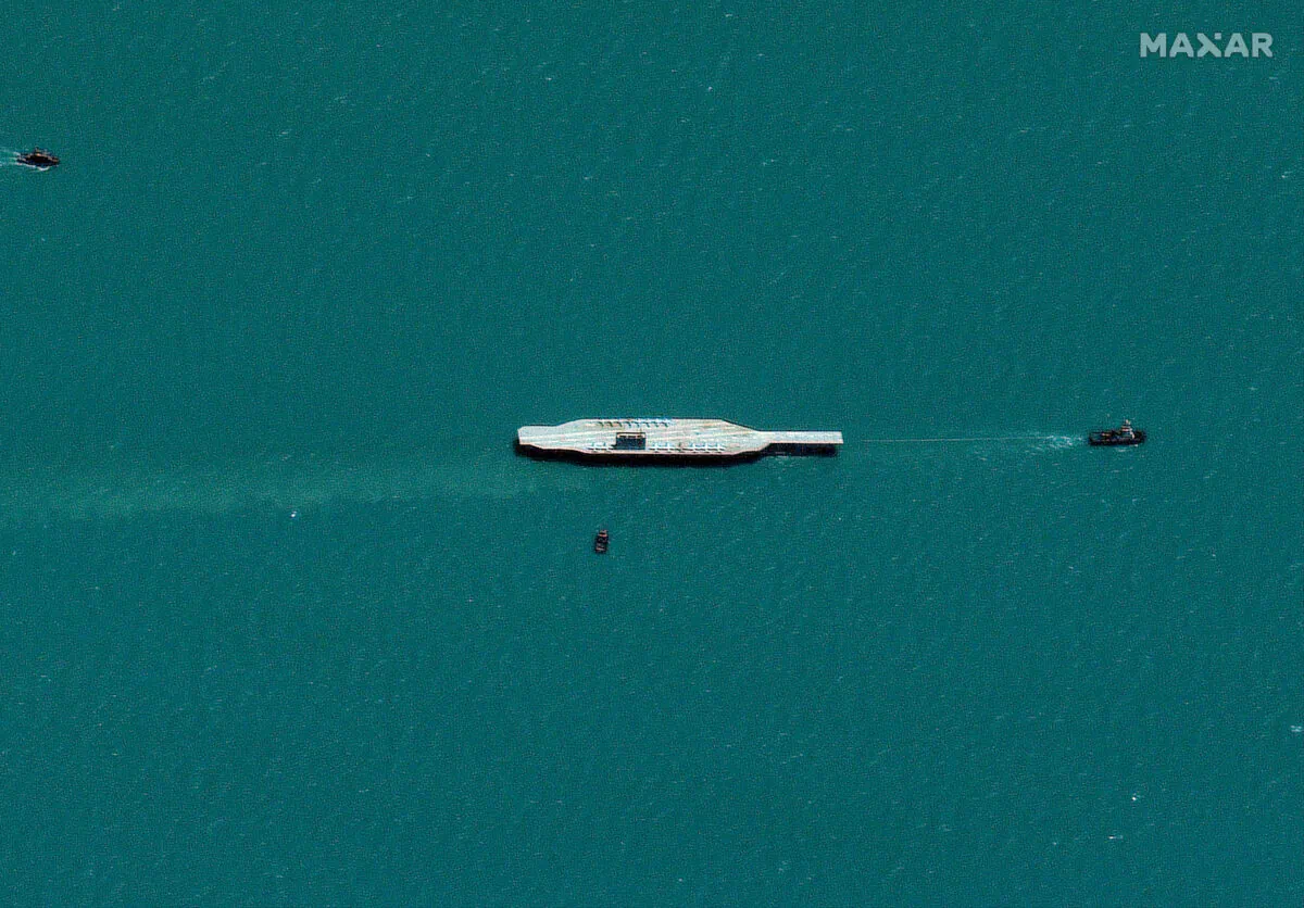 Iran's refurbished mock-up aircraft carrier (R), used previously as a simulated U.S. target during a February, 2015 Iranian naval war games exercise, is approached by a fast boat at the Strait of Hormuz, southeast of Bandar Abbas, Iran, on July 26, 2020. (Satellite image ©2020 Maxar Technologies/via Reuters)