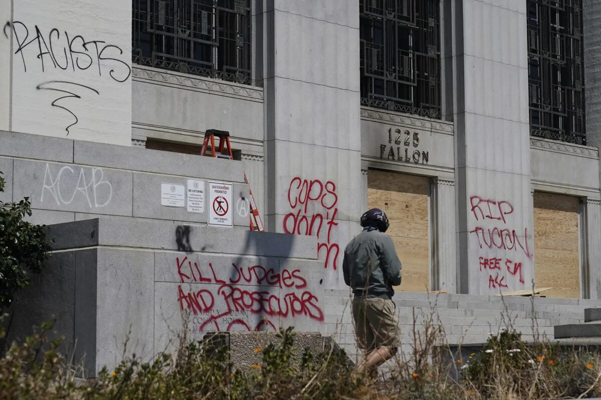 A man looks toward wooden boards and graffiti outside of the Alameda County Courthouse in Oakland, Calif., on July 26, 2020. (Jeff Chiu/AP Photo)