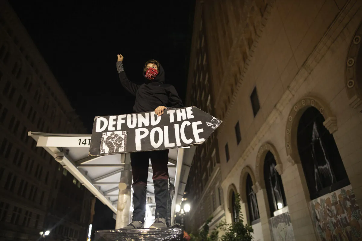 A demonstrator holds a sign during a riot in Oakland, Calif., on July 25, 2020. (Christian Monterrosa/AP Photo)