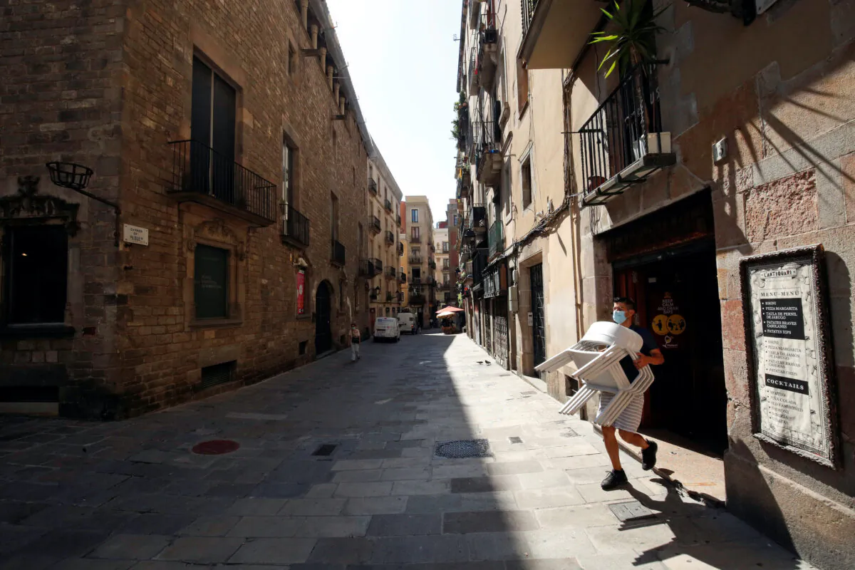A staff member of a bar carries chairs, amid the coronavirus disease (COVID-19) outbreak, in the Gothic quarter in Barcelona, Spain, on July 27, 2020. (Albert Gea/Reuters)