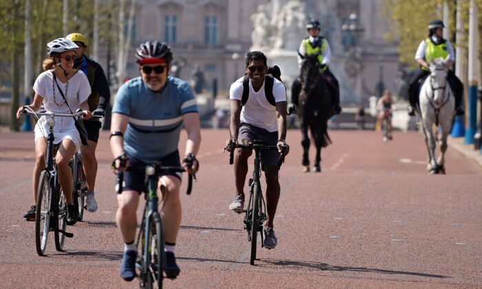 Cyclists ride their bicycles on The Mall road, outside Buckingham Palace in central London on April 11, 2020. (Photo by Niklas Halle'n/AFP via Getty Images)