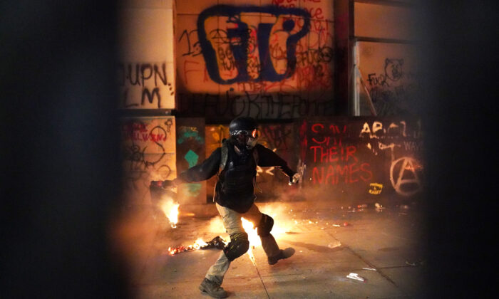 A rioter throws a flaming object toward the Mark O. Hatfield U.S. Courthouse after breaking through the perimeter fence, in Portland, Ore., on July 22, 2020. (Nathan Howard/Getty Images)