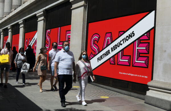 Pedestrians wearing face masks walk past Selfridges store Oxford Street