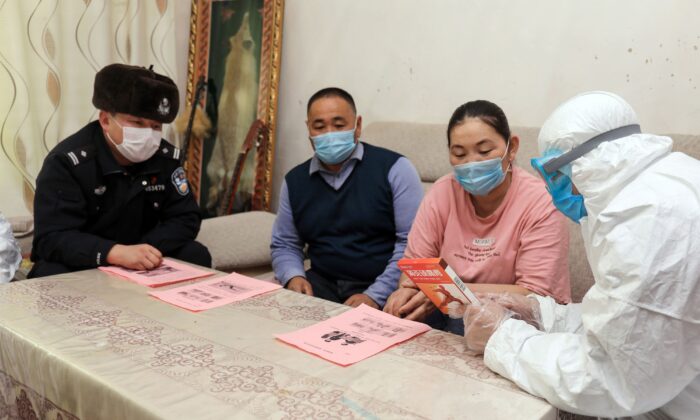 Police officers (L and R) visit residents to promote the awareness of COVID-19 in remote areas in Altay, China's Xinjiang region, on Feb. 19, 2020. (STR/AFP via Getty Images)