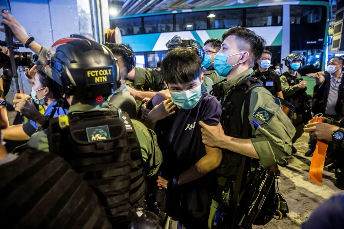 A riot police officer (R) detains a man (C) during a protest by district councillors at a mall in Yuen Long in Hong Kong on July 19, 2020, against a mob attack by suspected triad gang members inside the Yuen Long train station, on July 21, 2019. (Isaac Lawrence/AFP via Getty Images)