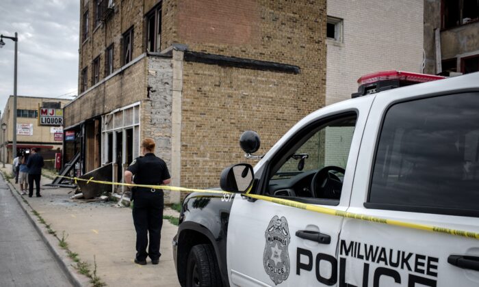 A police officer stands before the remains of a bar in Milwaukee, Wisconsin, on Aug. 15, 2016. (Cengiz Yar/AFP via Getty Images)