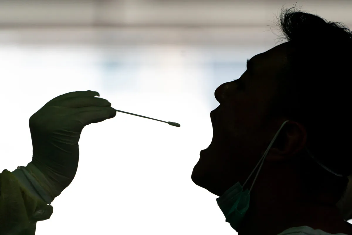 A medical professional is collecting a swab sample from a taxi driver for COVID-19 test at a makeshift testing station in Hong Kong on July 24, 2020. (Anthony Kwan/Getty Images)