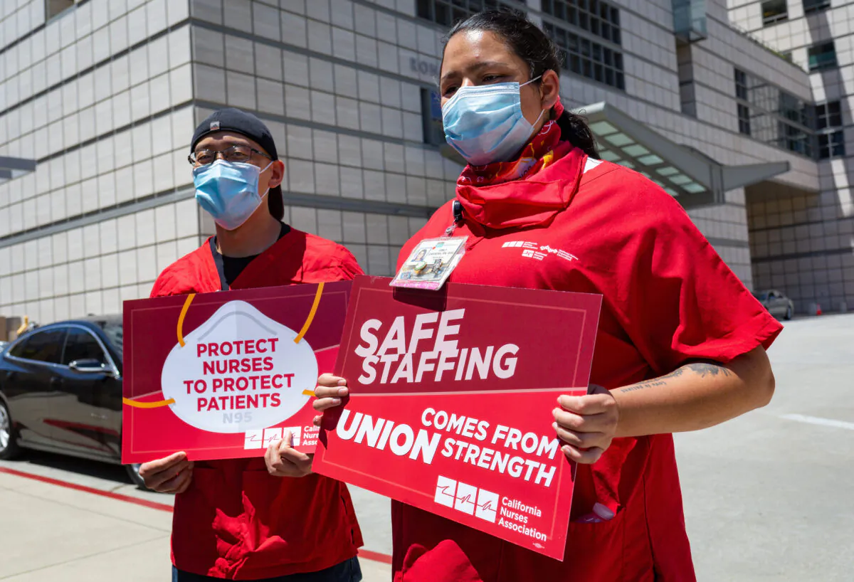 Nurses David Yamada, left, and Emily Carrera hold signs at a protest over working conditions due to the COVID-19 pandemic outside the Ronald Reagan UCLA Medical Center in Los Angeles, Calif., on July 29, 2020. (John Fredricks/The Epoch Times)