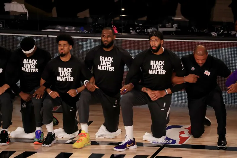 LeBron James (C) and Anthony Davis (2nd R) of the Los Angeles Lakers kneel with other players and personnel during the national anthem prior to the game against the LA Clippers at The Arena at ESPN Wide World Of Sports Complex in Lake Buena Vista, Fla., on July 30, 2020. (Mike Ehrmann/Pool via USA TODAY Sports)