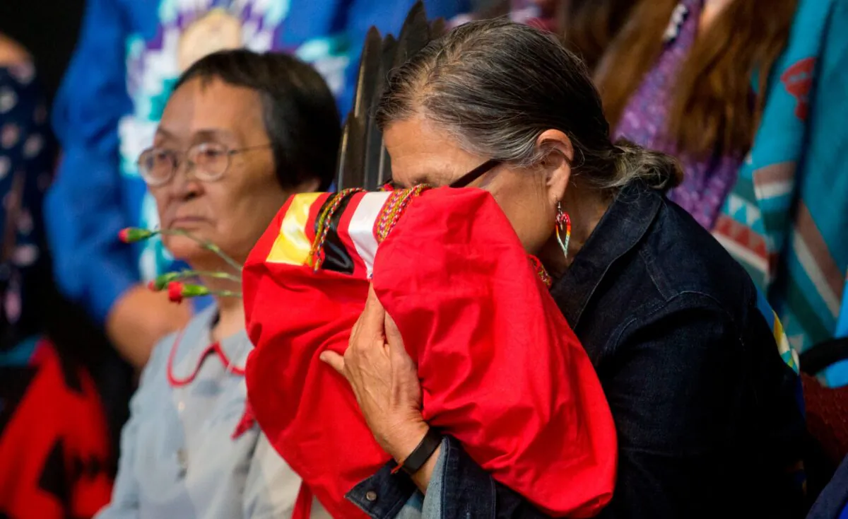 An elder indigenous woman embraces the final copy of the National Inquiry into Missing and Murdered Indigenous Women and Girls at a public closing ceremony marking the conclusion of the inquiry at the Museum of History in Gatineau, Quebec on June 3, 2019. (Andrew Meade/AFP via Getty Images)