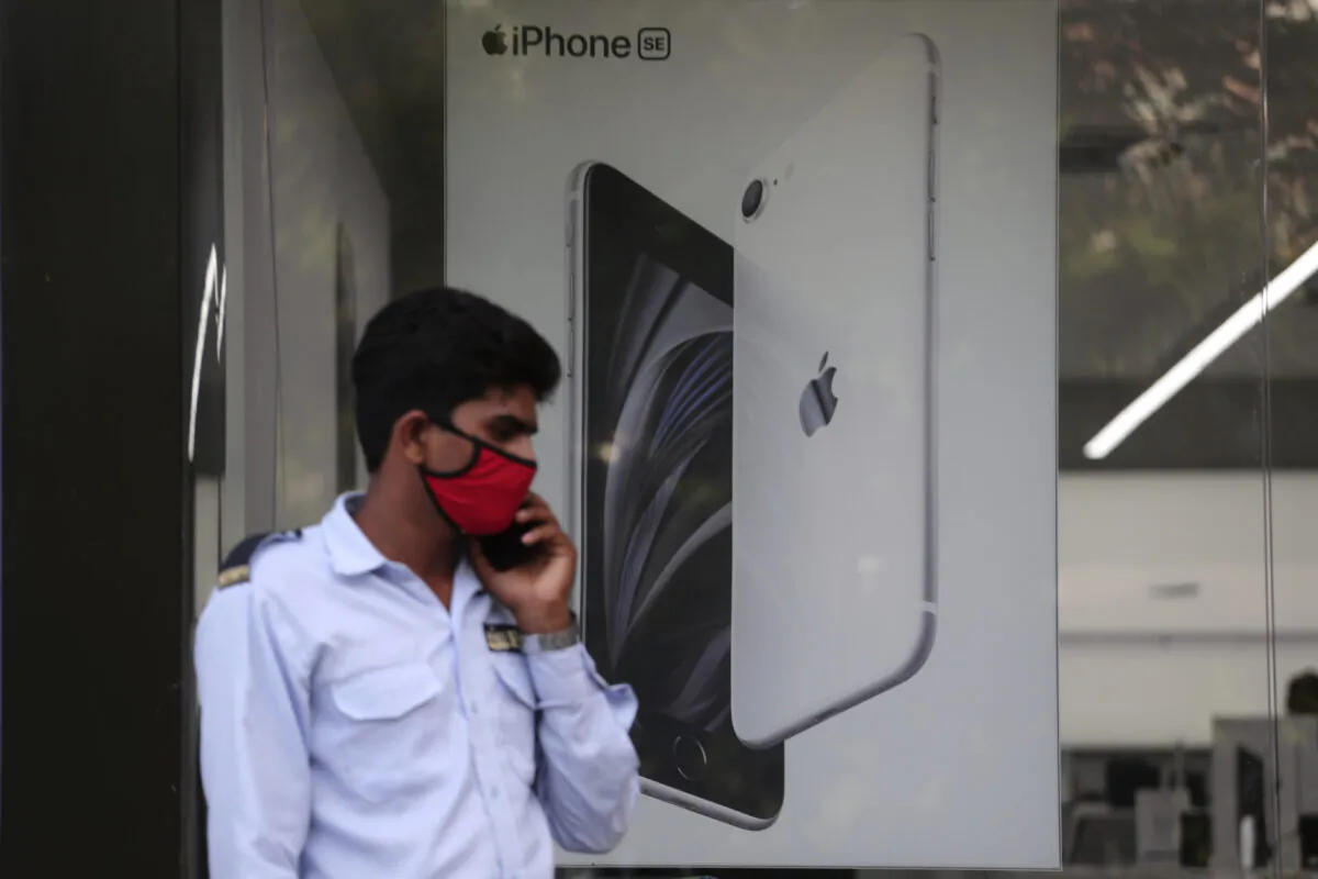 A security officer talks on a phone in front of an image of an iPhone displayed at an Apple store in Ahmedabad, India, on Aug. 1, 2020. (Ajit Solanki/AP Photo)
