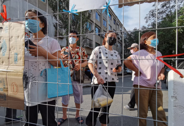 Residents wait for groceries delivered to an entrance of a sealed residential compound in Dalian