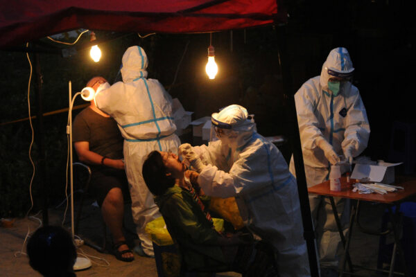 Workers in protective suits collect swabs for nucleic acid testing at a makeshift testing site, following the coronavirus disease (COVID-19) outbreak in Dalian, China, on July 26, 2020. (China Daily via Reuters)