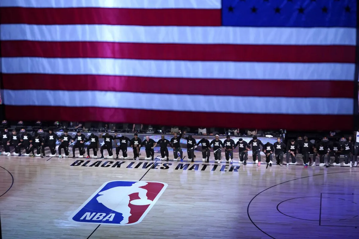 Members of the Orlando Magic and Brooklyn Nets kneel around a Black Lives Matter logo during the national anthem before the start of an NBA basketball game in Lake Buena Vista, Fla., on July 31, 2020. (Ashley Landis/AP Photo)