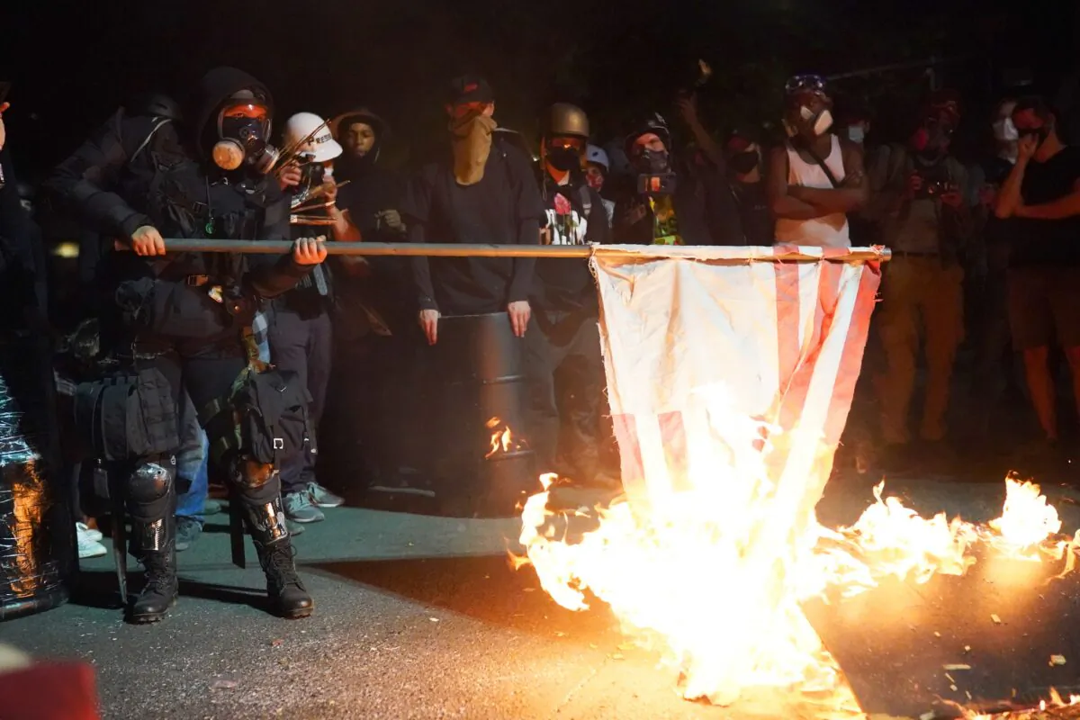 A demonstrator burns an American flag in front of the Mark O. Hatfield Courthouse in the early morning in Portland, Ore., on Aug. 1, 2020. (Nathan Howard/Getty Images)