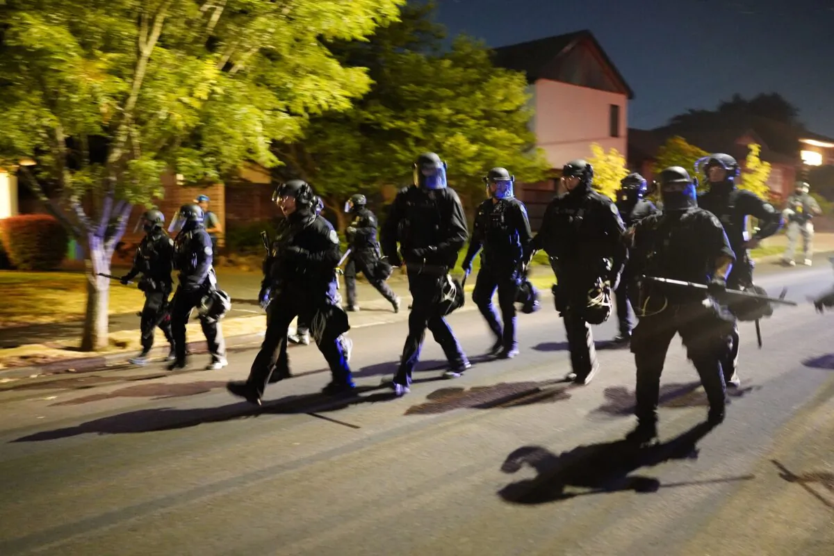 Portland police officers pursue a crowd of about 200 after forcing the group to disperse from a law enforcement precinct in Portland, Ore., late Aug. 1, 2020. (Nathan Howard/Getty Images)